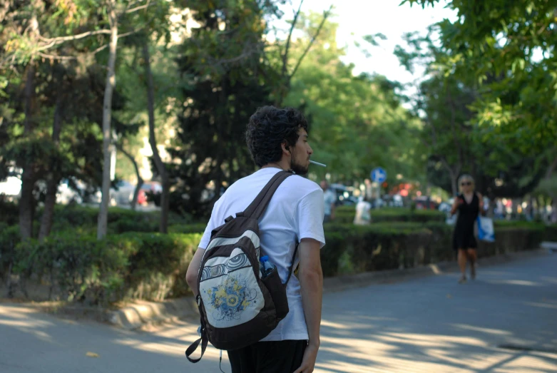 young man with backpack looking down the street