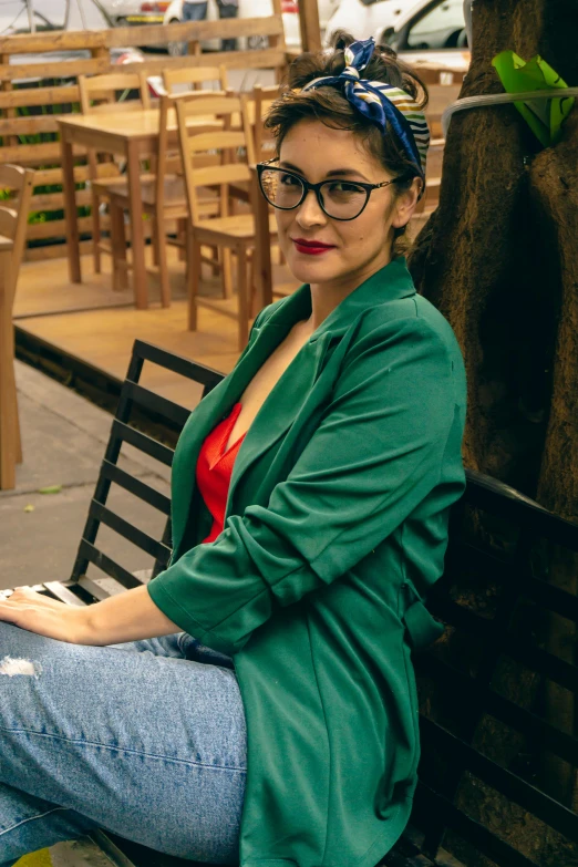 a young woman in glasses is sitting on a wooden bench