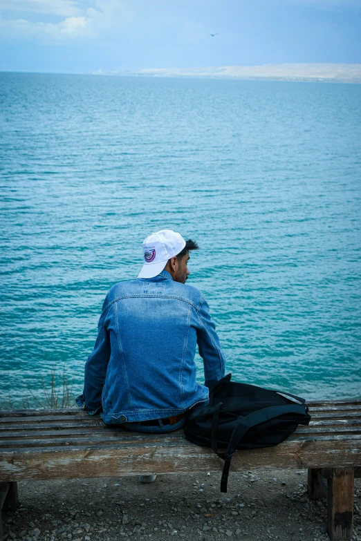 a man sitting on a bench looking out to sea