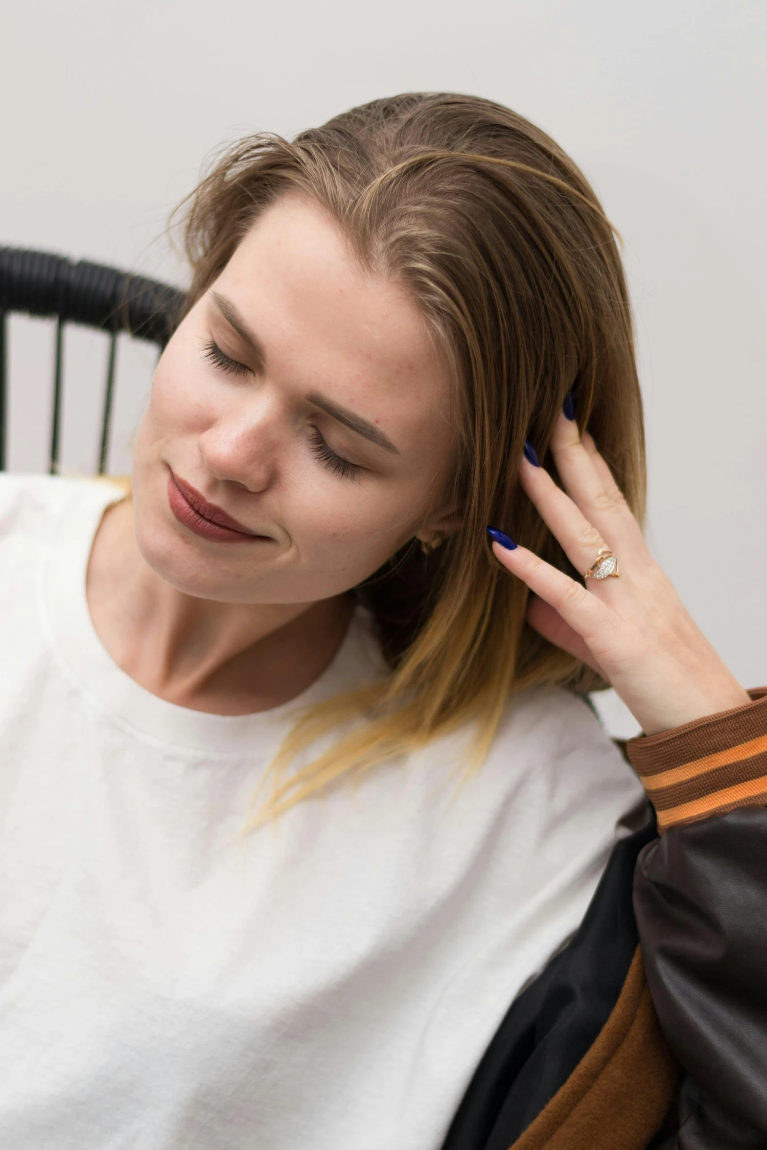 a woman in a black and white jacket holds a hairbrush near her ear