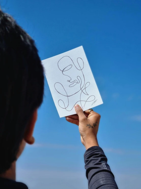 a person is holding up a paper drawing