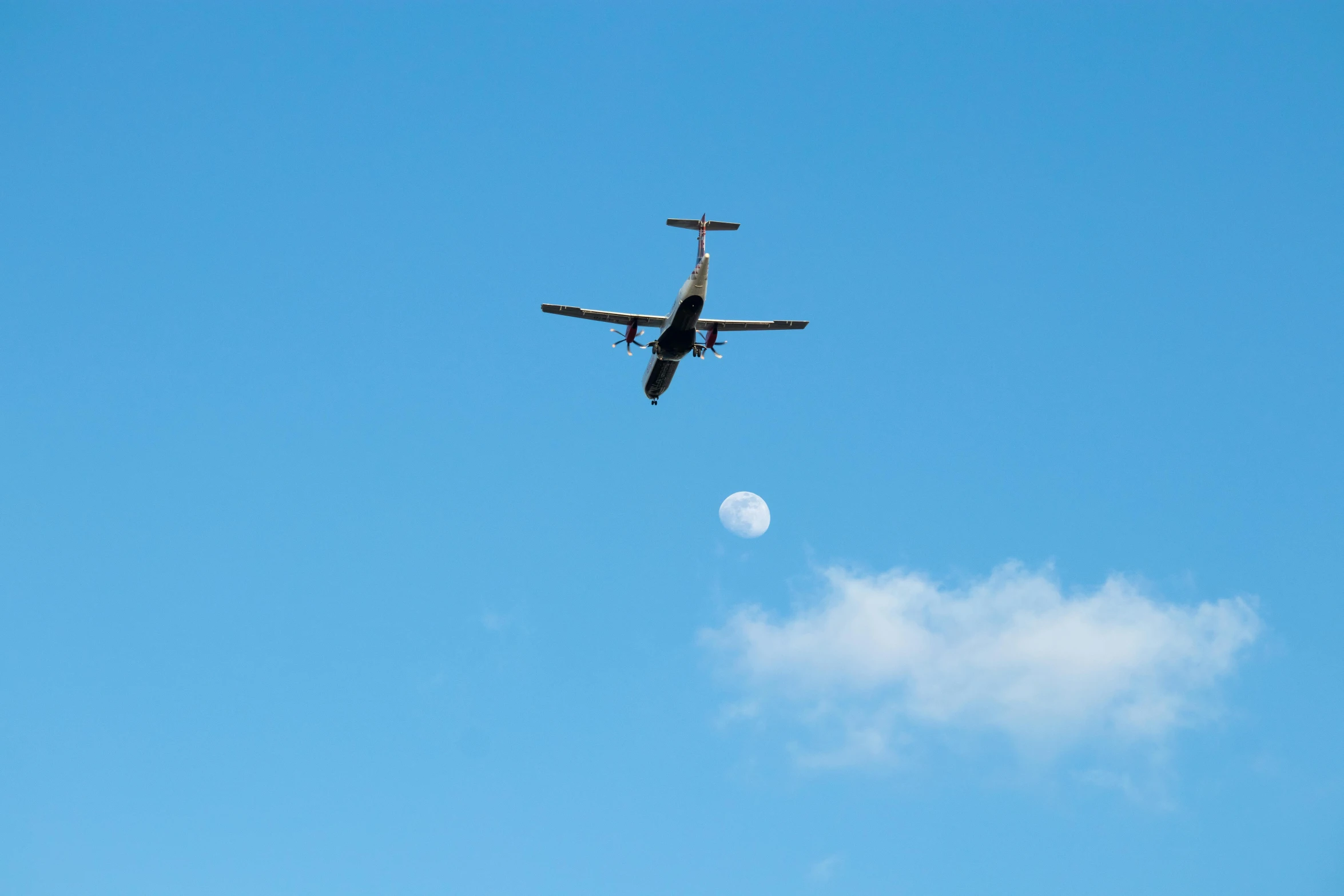 an airplane flying in the sky with a moon behind it