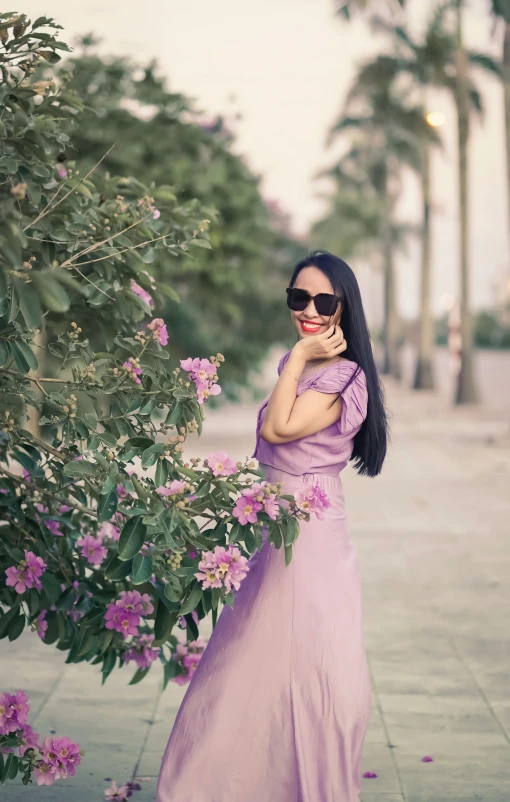 a woman in a lavender colored dress poses with pink flowers