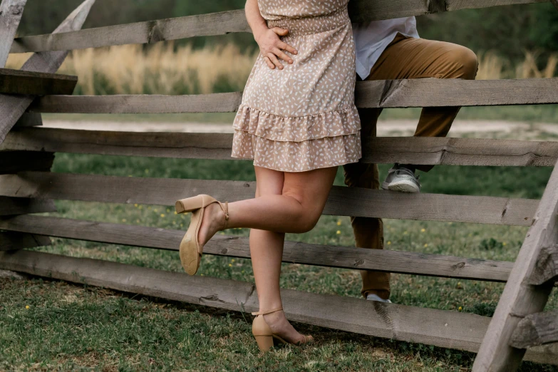 a young woman and man leaning against a fence together