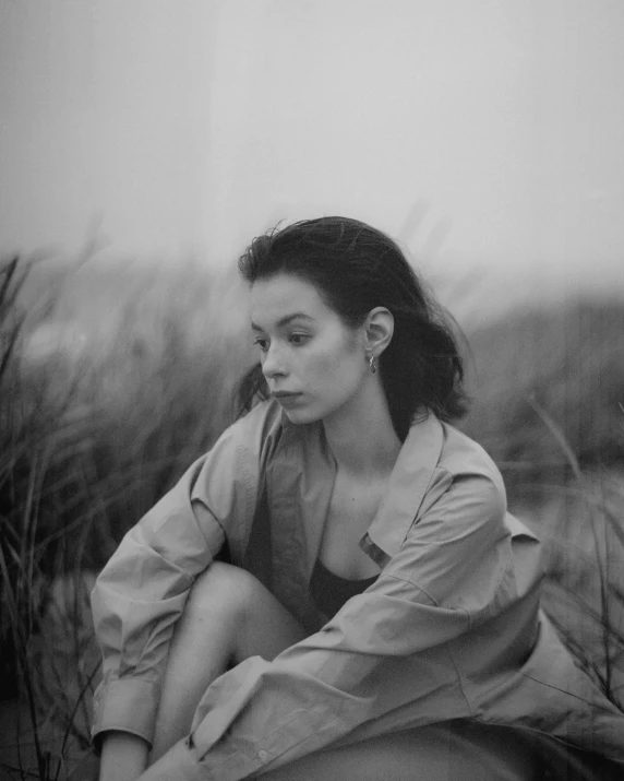 a woman sitting in tall grass near an ear plant