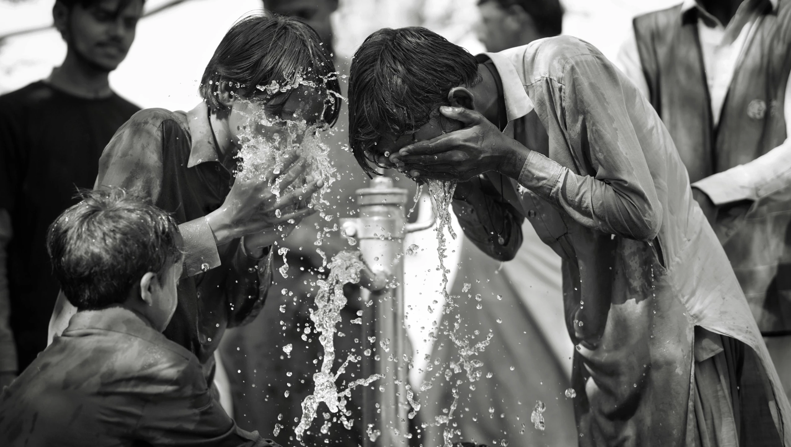 people who are washing their faces and bodies with water