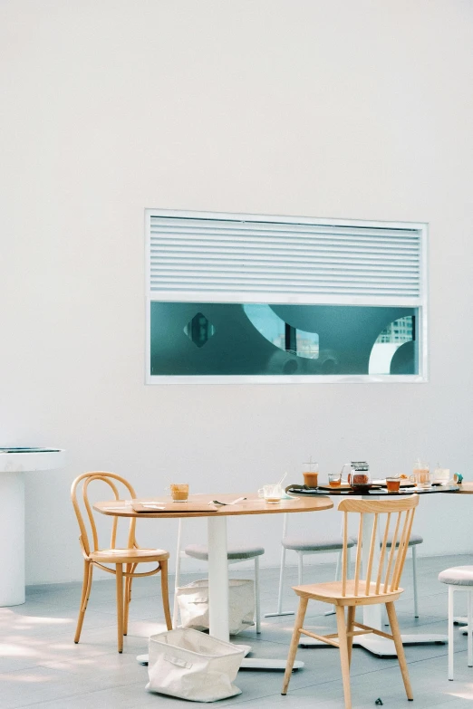 a table and chairs are in a white room with a large window