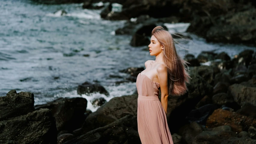 a girl stands in front of the ocean looking at the waves