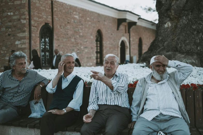 several men sitting on a wooden bench outdoors