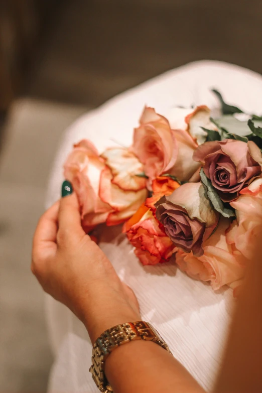 hands holding onto a bouquet of flowers on a table