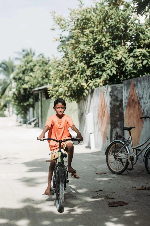 a boy riding on top of a bicycle down a sidewalk