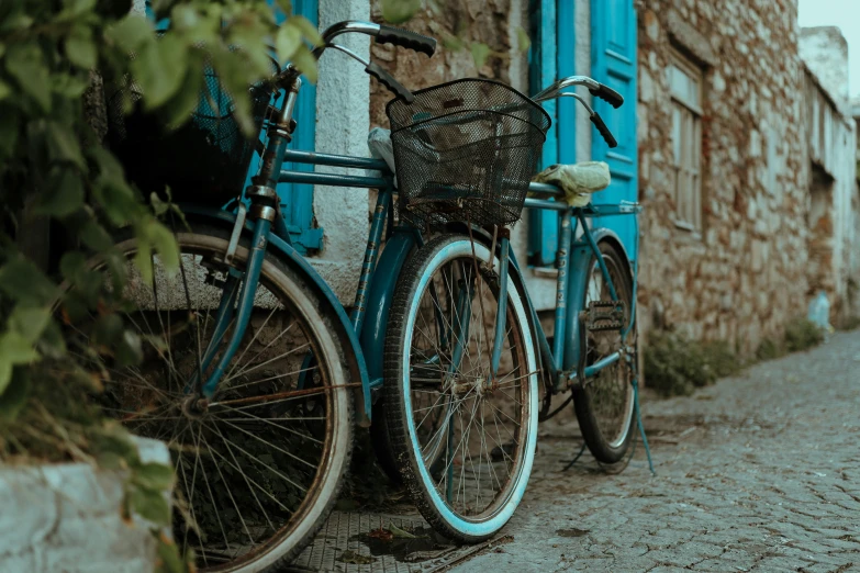 two blue bicycles parked side by side next to a building