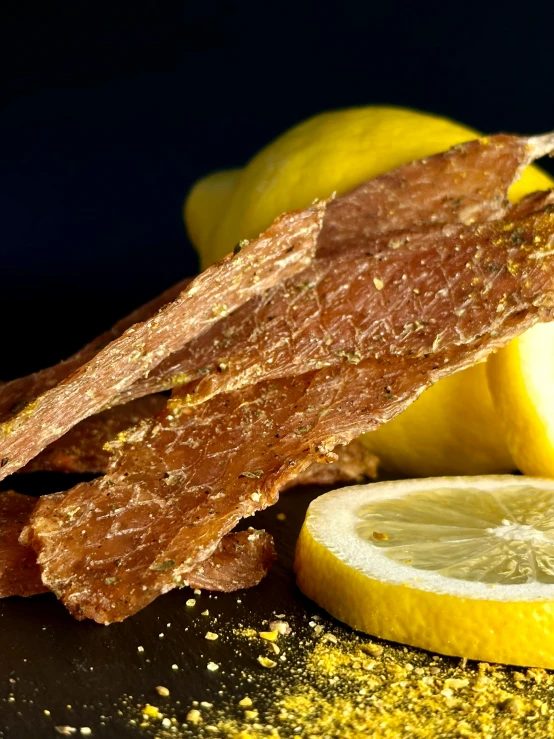 a pile of raw sliced up meat sitting next to two lemons