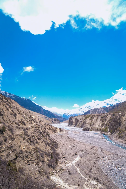 a river running through some mountains surrounded by greenery