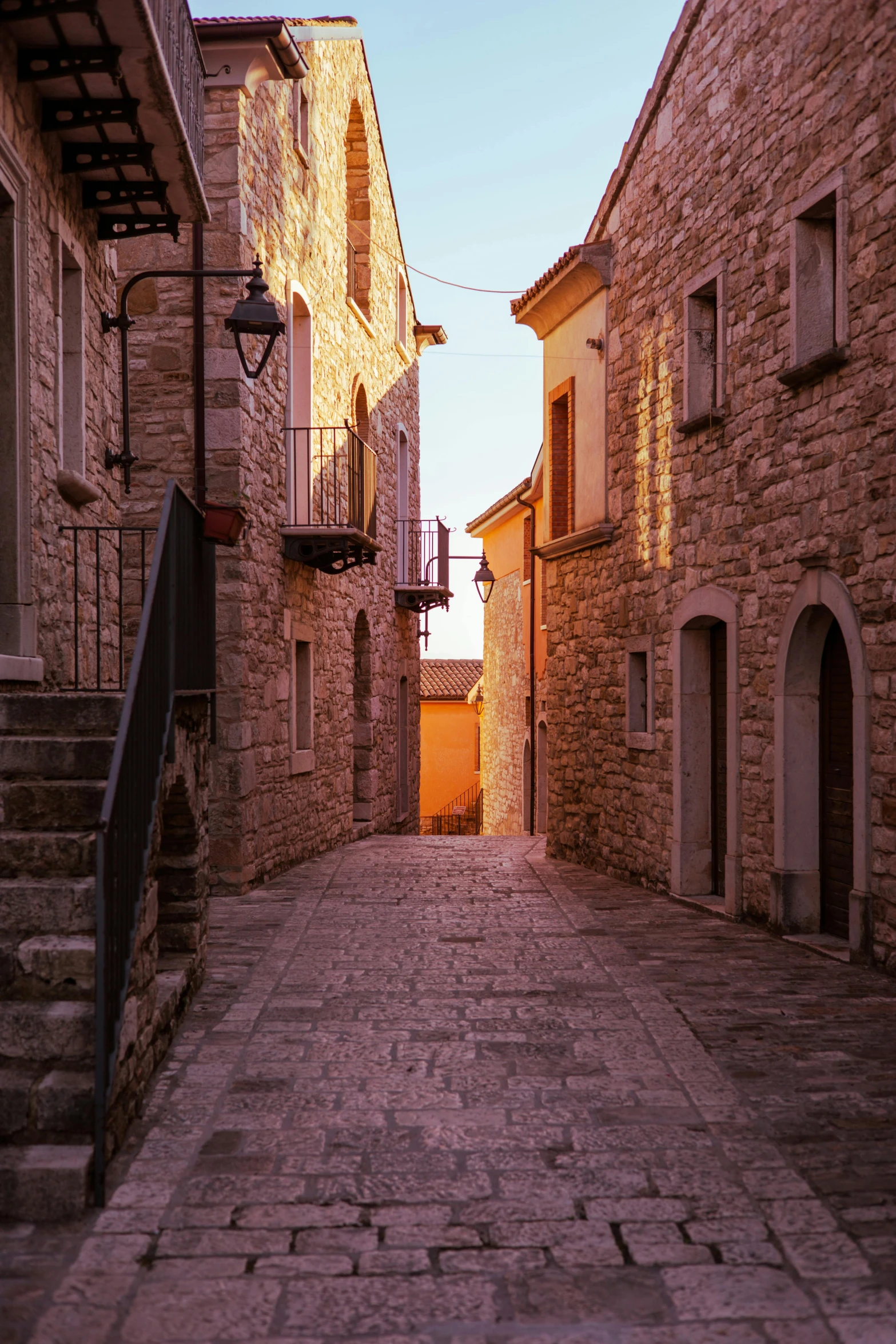 narrow cobblestone alleyway with stone buildings lining side of street