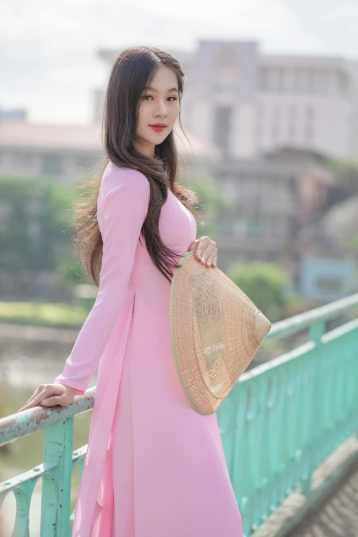 a woman in a pink dress standing on a bridge