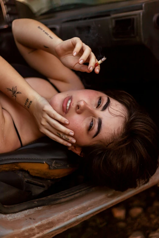 a woman with piercings is laying down on a brown chair