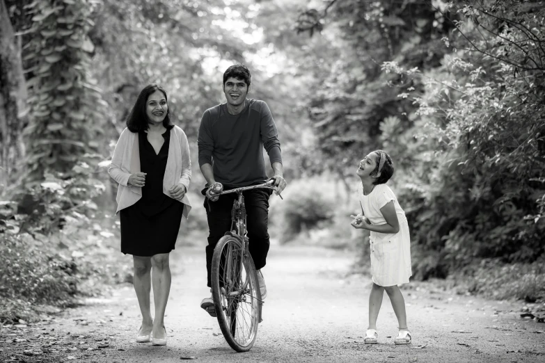 a family holding hands walking their bicycle in the woods