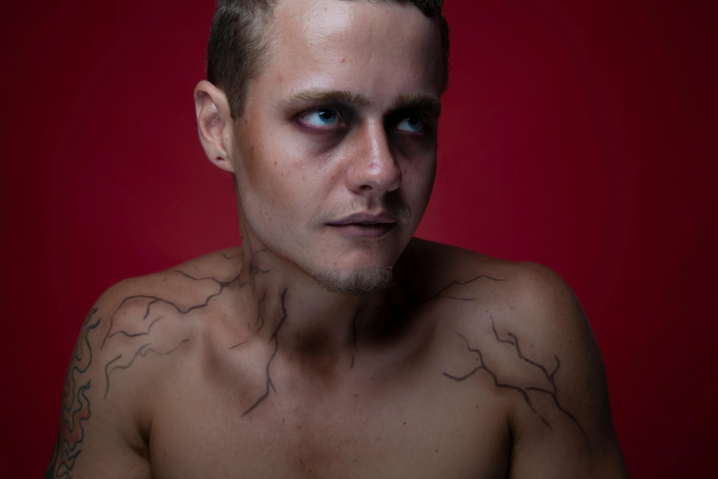 a man with a tattoo on his chest, and red background