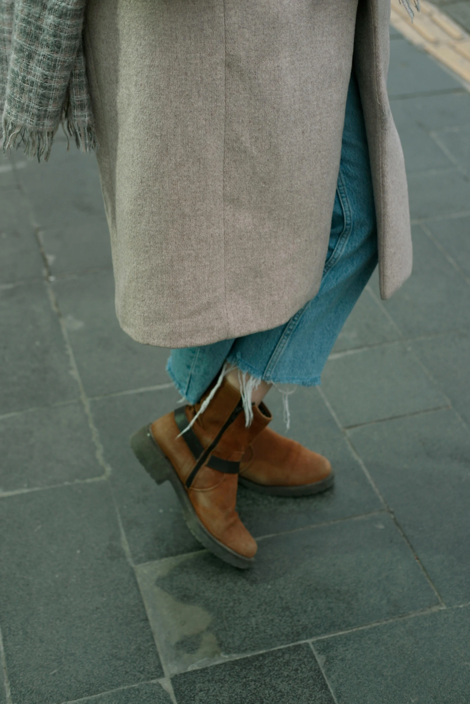 a person's legs and boots as they walk on a sidewalk