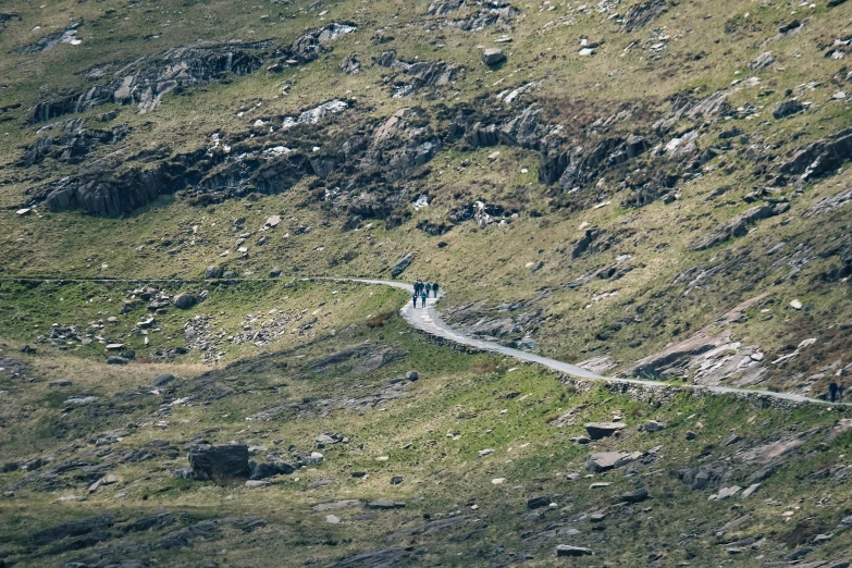 a hiker treks up a trail on a steep mountain