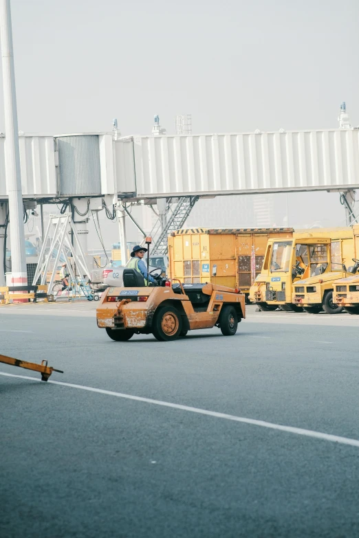 a yellow vehicle traveling down a road next to an overpass