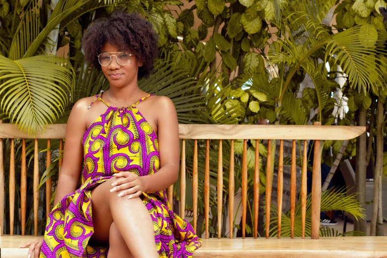 the woman is sitting on a bench wearing a colorful dress