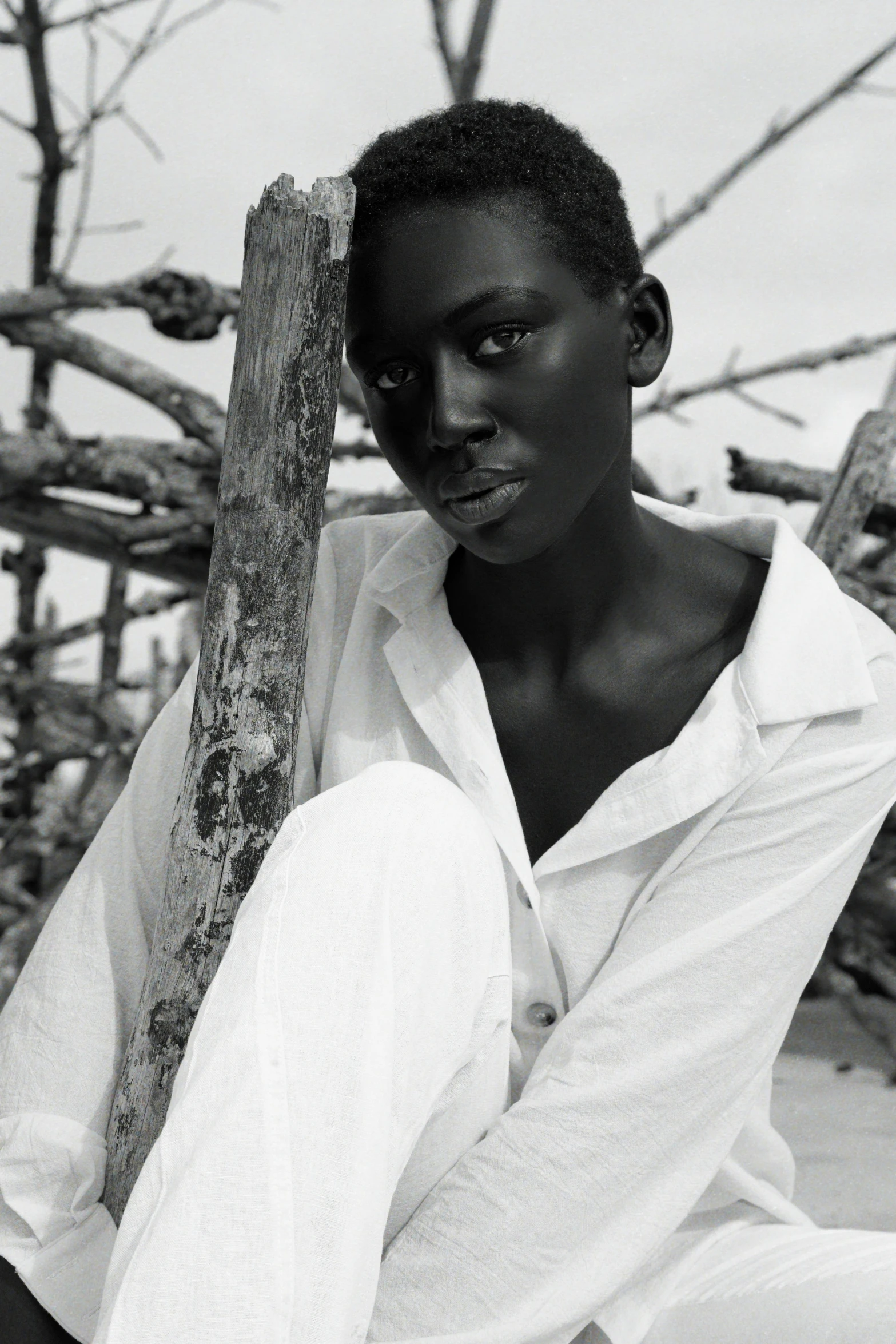 a black and white po of a young woman leaning against a tree trunk