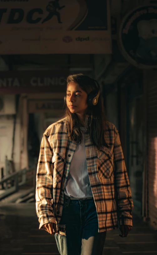 the girl is walking through an alley way with ear buds on