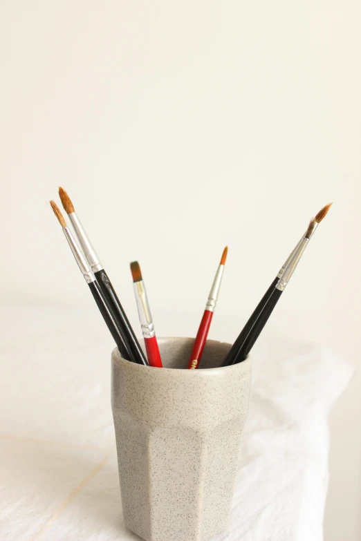 a white cup with a variety of paint brushes in it