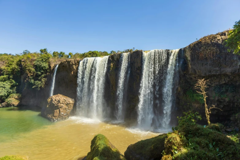 water spilling over a waterfall near rocks and trees