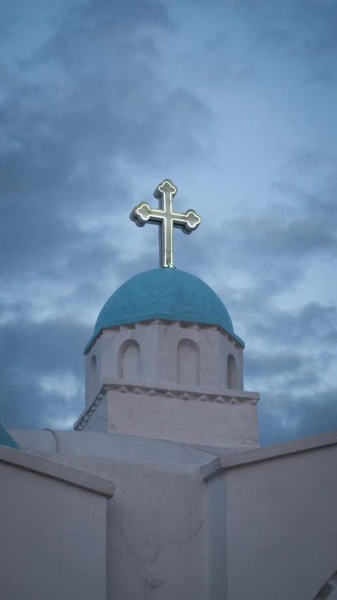 a white building with a blue domed roof and a cross