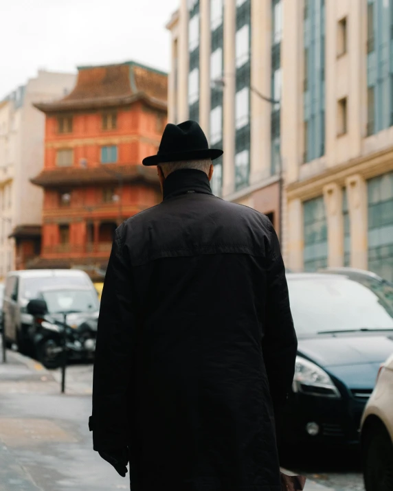 a man walking down a street while wearing a hat