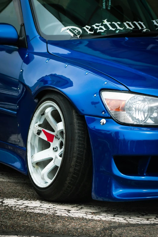 blue bmw car with a license plate and a red sports tire