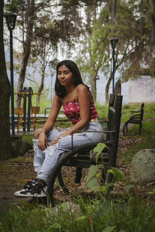 a woman is sitting on a bench in the woods