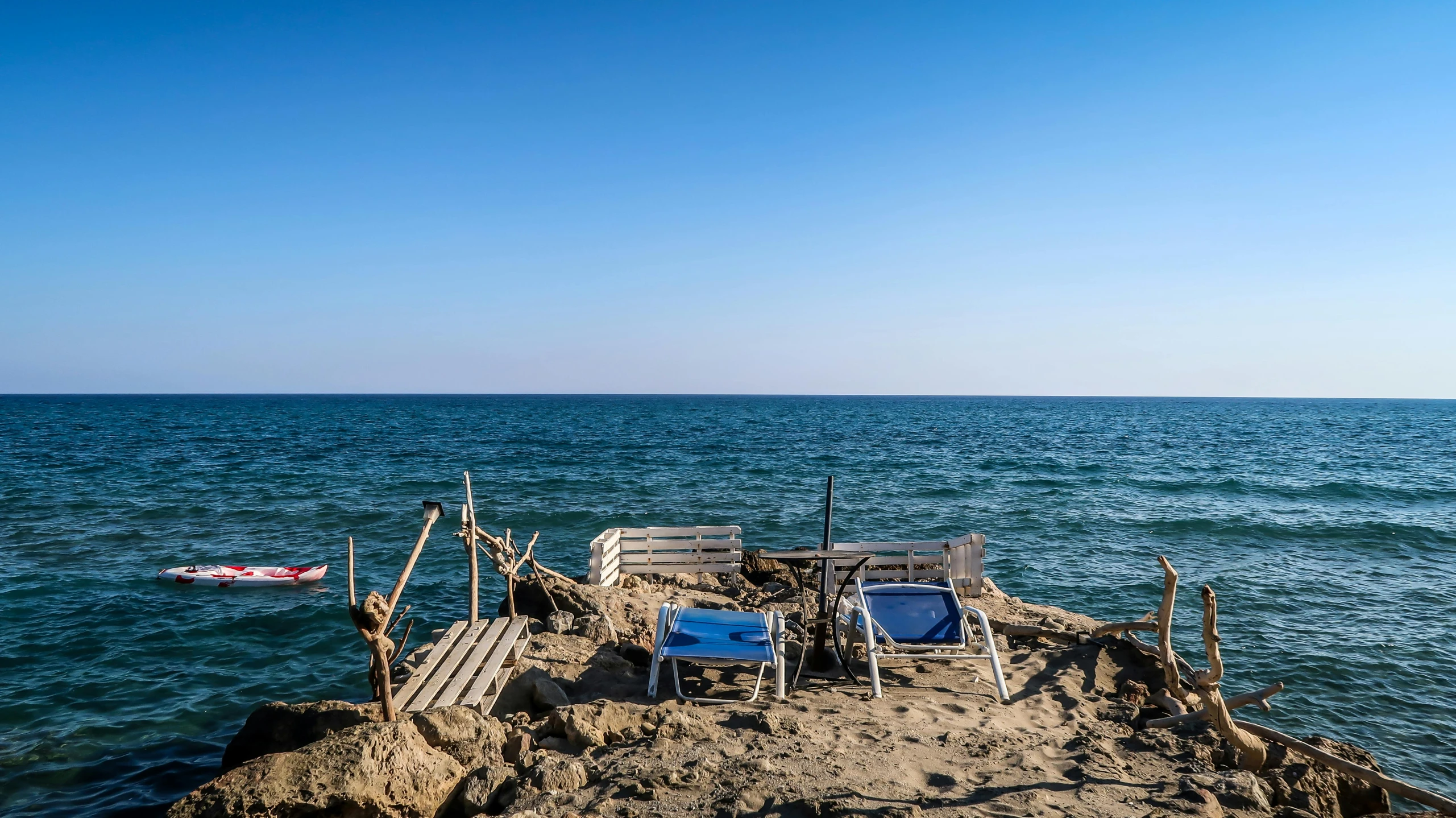 four chairs and two boats sitting on a rocky outcropping