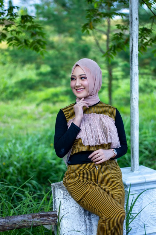 an attractive woman posing for the camera with a green forest behind her