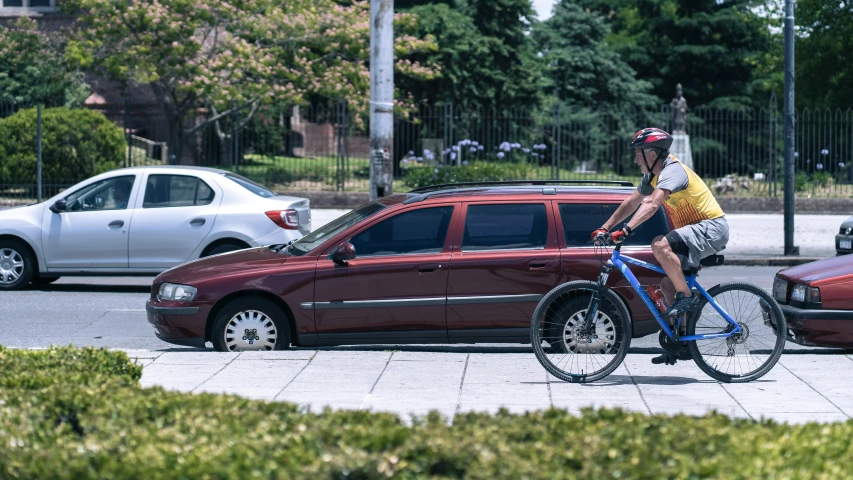 a man riding a bicycle down a sidewalk next to cars