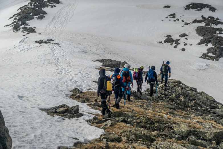 a group of people climbing uphill with backpacks