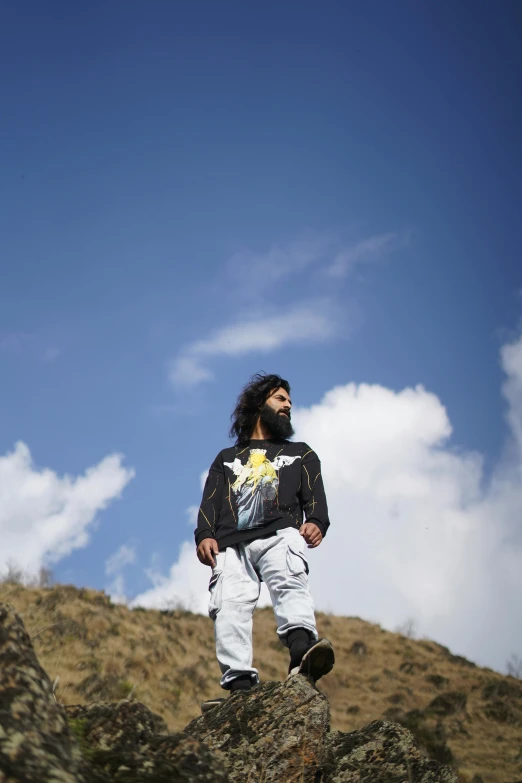 man standing on rock next to open blue sky