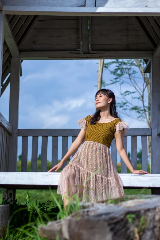 a woman poses at the end of a white bench