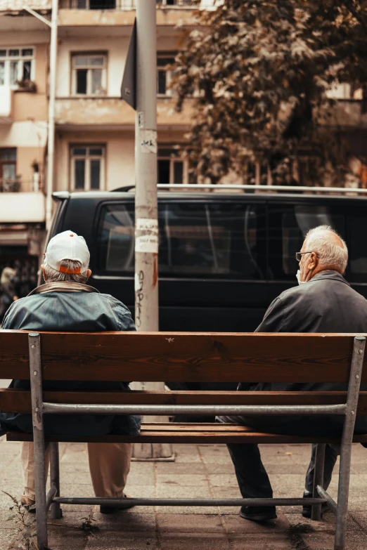 two older men are sitting on a bench