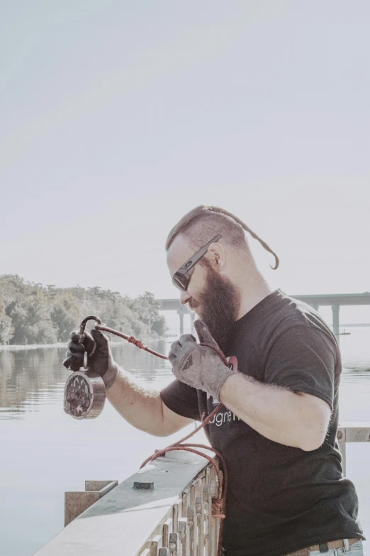 the man is holding an object up while sitting on a dock