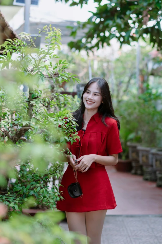 a smiling woman in a short red dress in the park