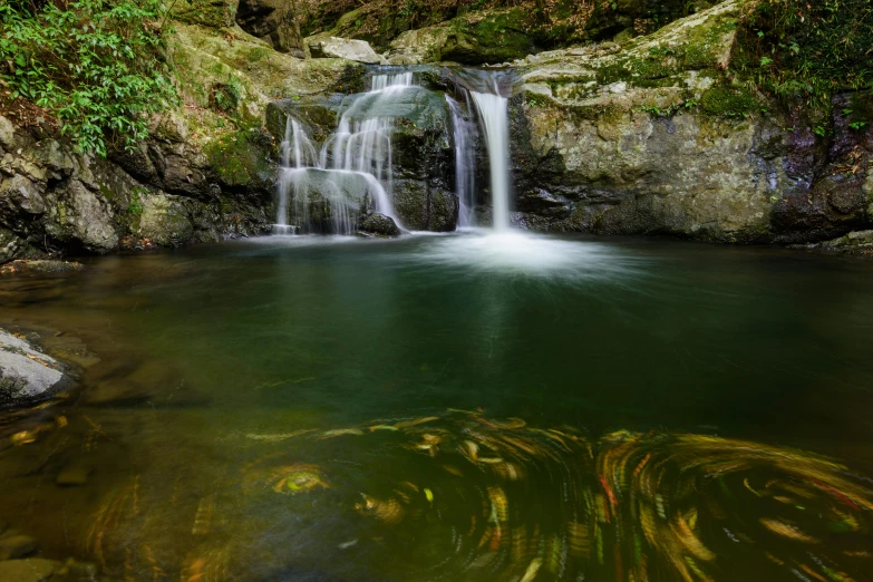 the waterfall has two cascades over rocks in a lake