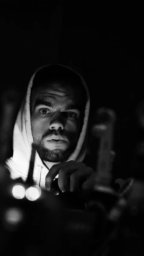 a man with a hood and lights on in the dark