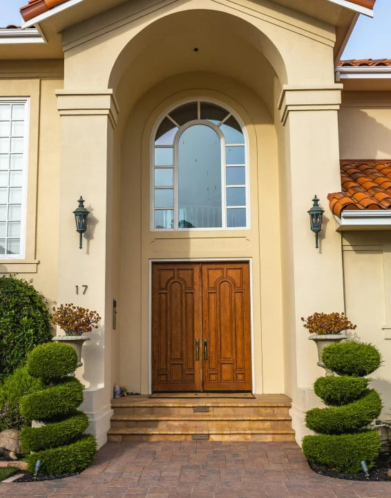 a house with bushes, shrubs and a wooden front door