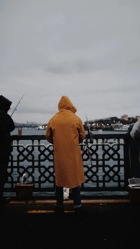 man in a yellow coat fishing on the water