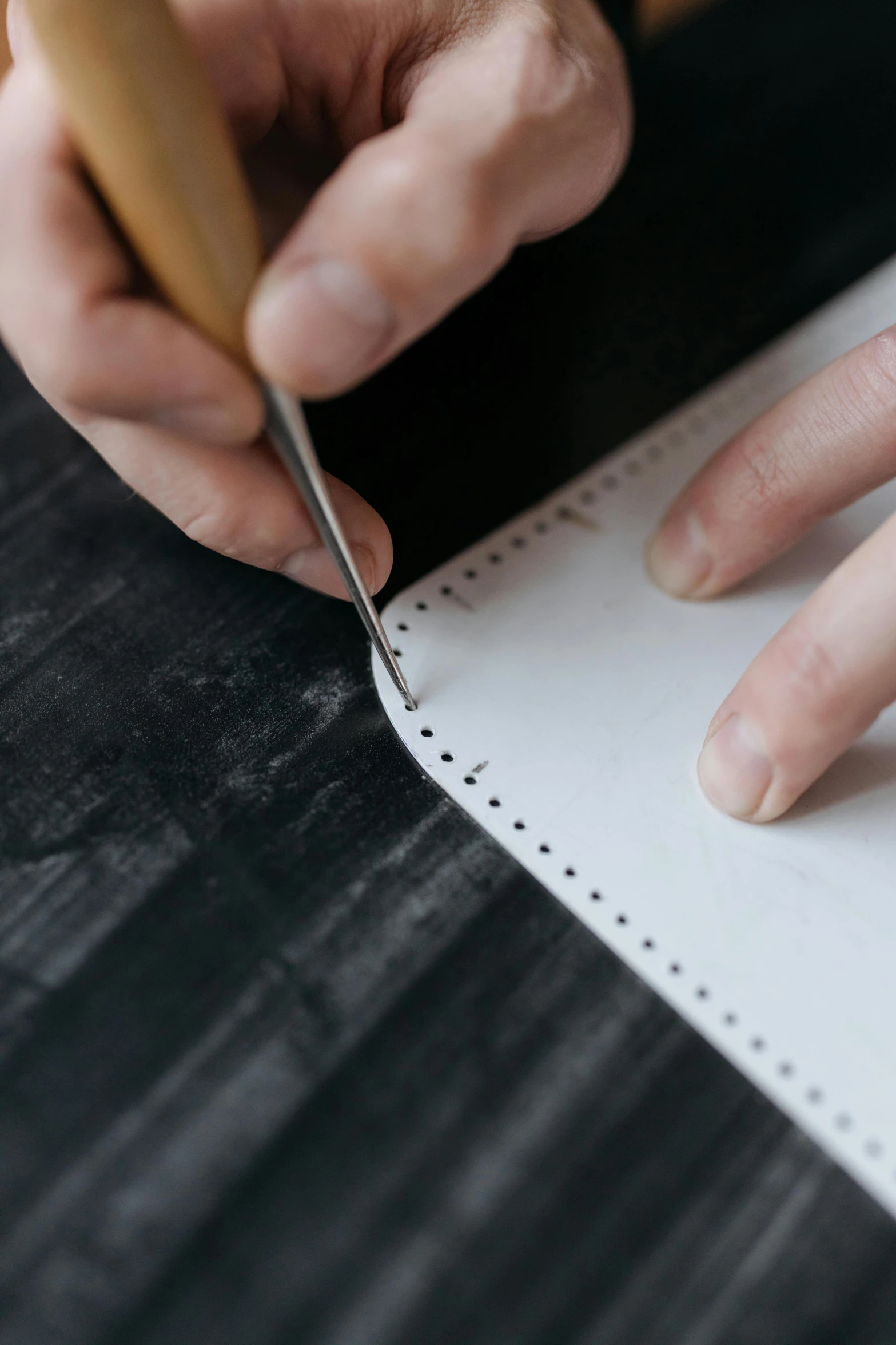 someone uses scissors to cut some paper on a table