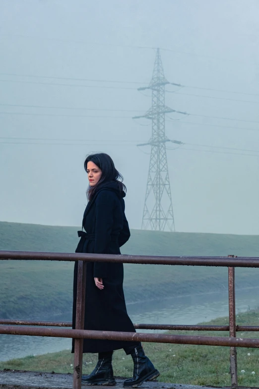 a woman standing next to a metal railing near a lake